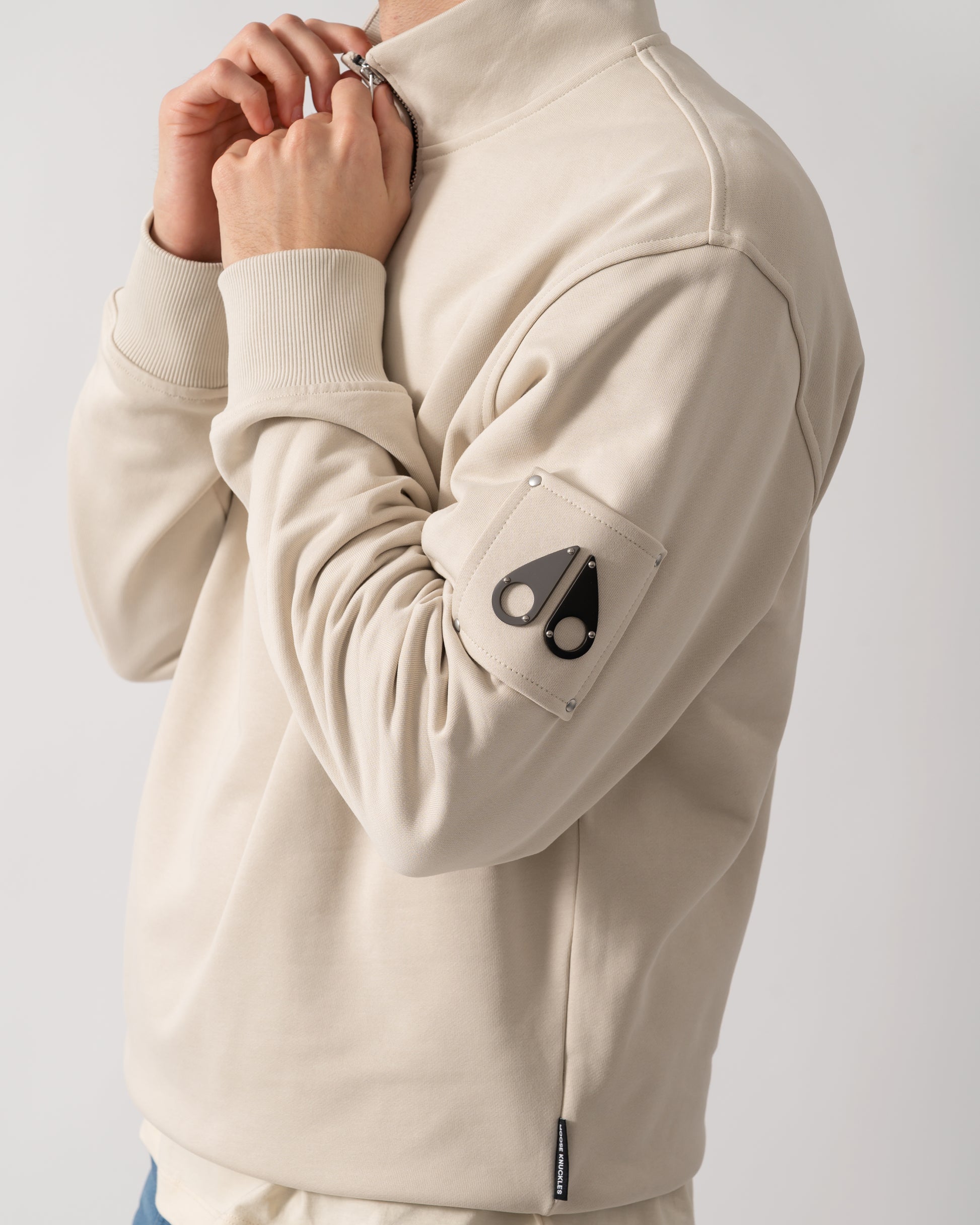 close up shot of a model wearing a Moose Knuckles Hartsfield Mens 1/4 Zip Sweatshirt in Alabaster 1705