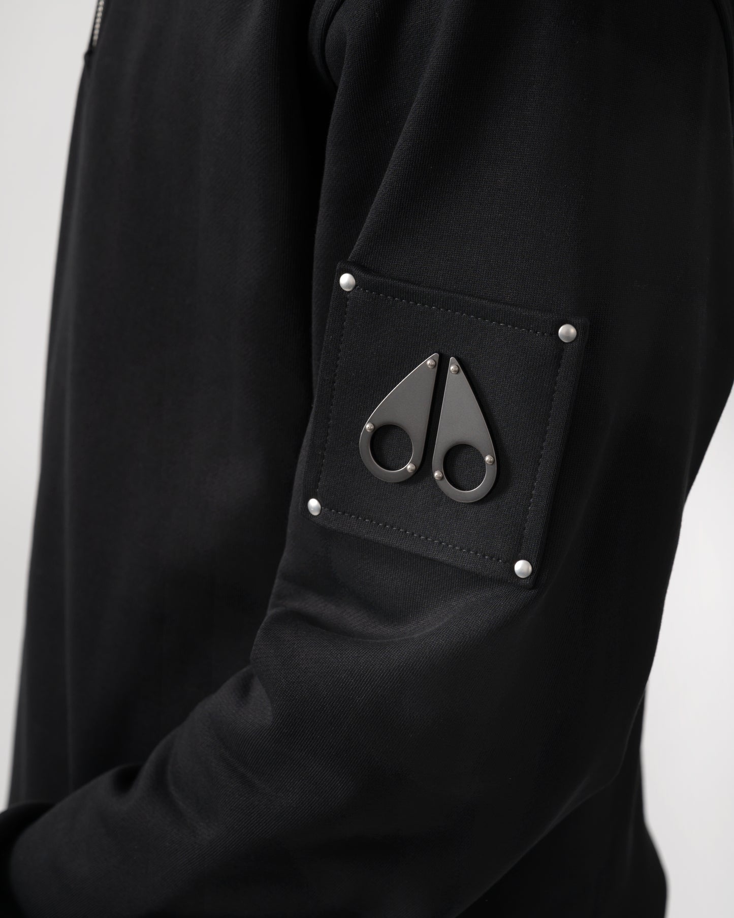 logo detail shot of a Moose Knuckles Hartsfield Mens quarter Zip Sweatshirt in Black 292