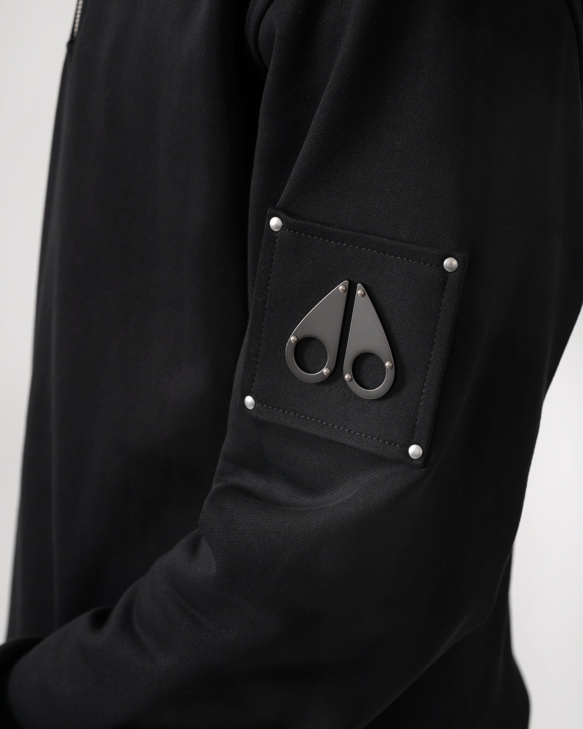 logo detail shot of a Moose Knuckles Hartsfield Mens quarter Zip Sweatshirt in Black 292