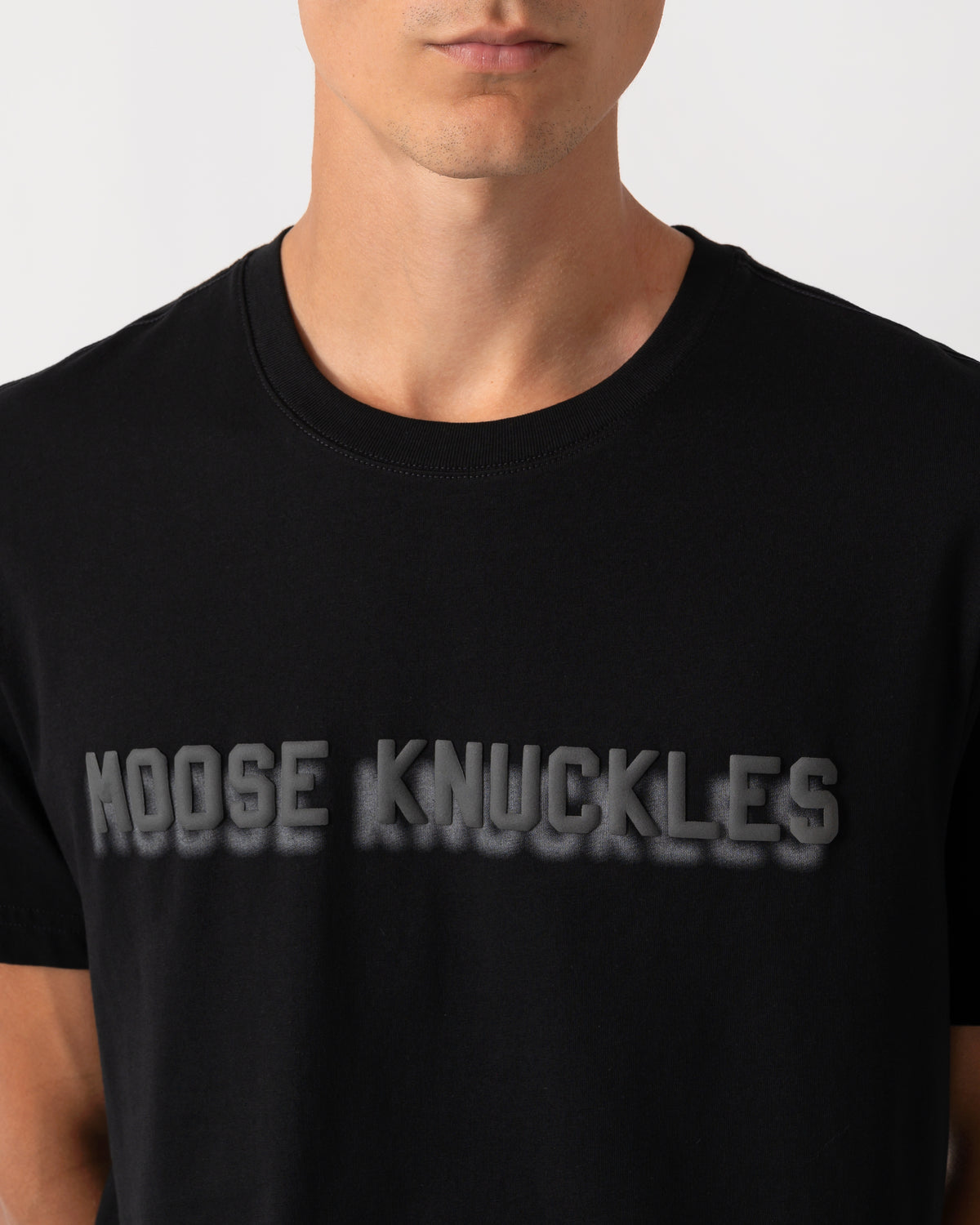 close up of a model wearing a Moose Knuckles Mens Shadow Logo T-Shirt in Black 292