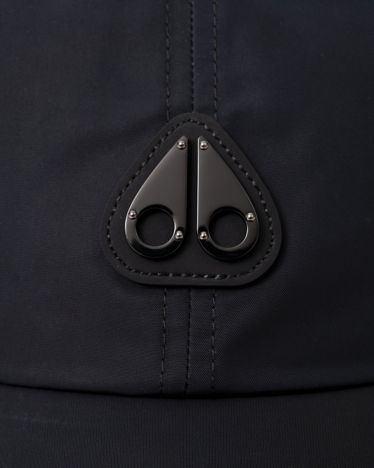 logo detail of a Moose Knuckles Mens Vick Cap in Black 292