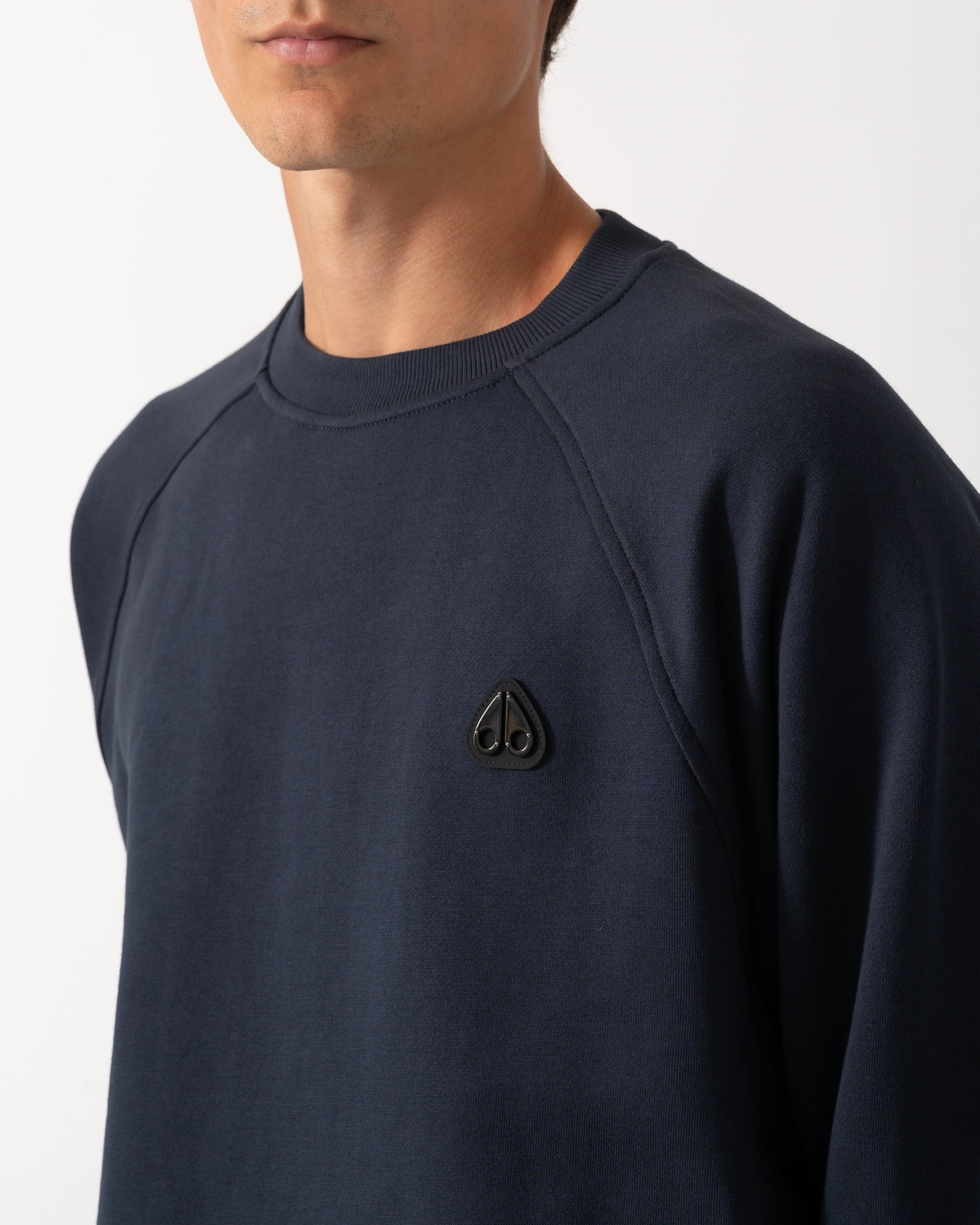 close up of model wearing a Moose Knuckles Mens Yul Crewneck Sweatshirt in Navy 833