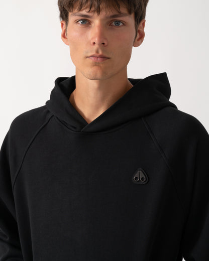 close up of a model wearing a Moose Knuckles Mens Yul Pullover Hoodie in Black 292
