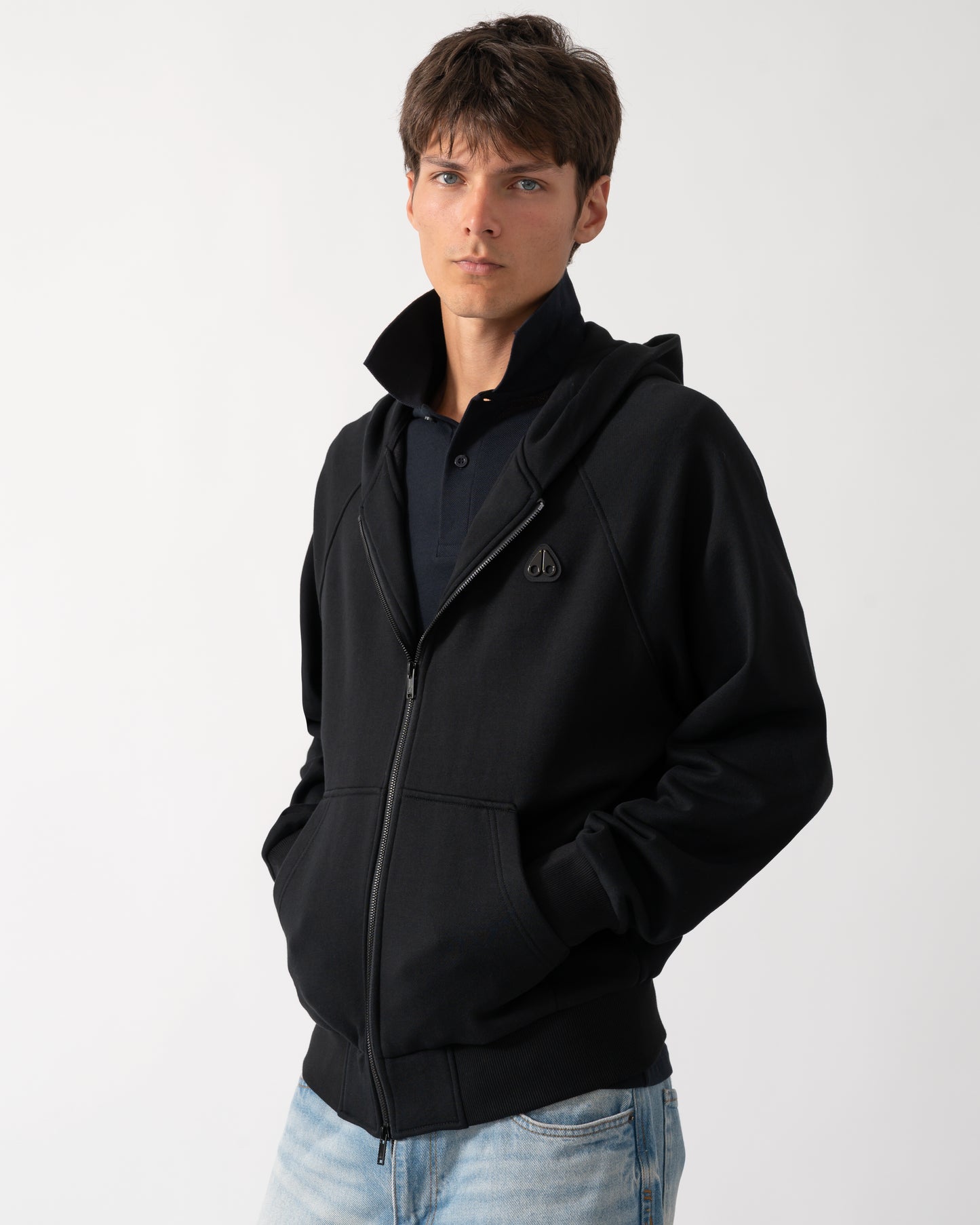 a model wearing a Moose Knuckles Mens Yul Zip Up Hoodie in Black 292