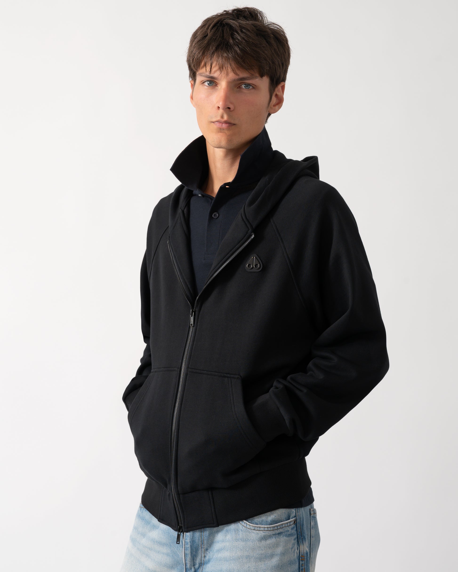 a model wearing a Moose Knuckles Mens Yul Zip Up Hoodie in Black 292