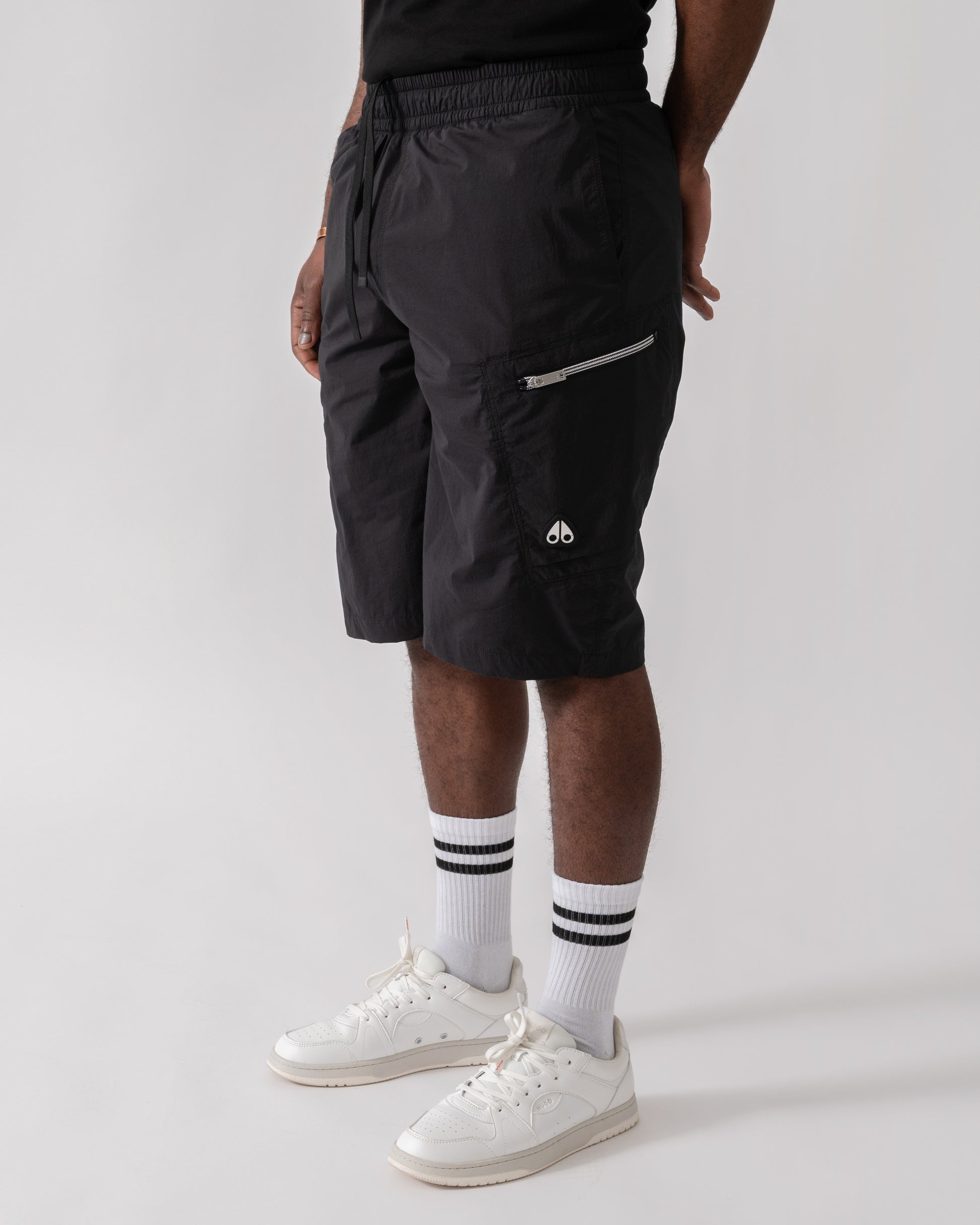 Model wearing Moose Knuckles Topflight Mens Cargo Shorts in Black 292 - side view