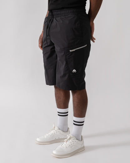Model wearing Moose Knuckles Topflight Mens Cargo Shorts in Black 292 - side view