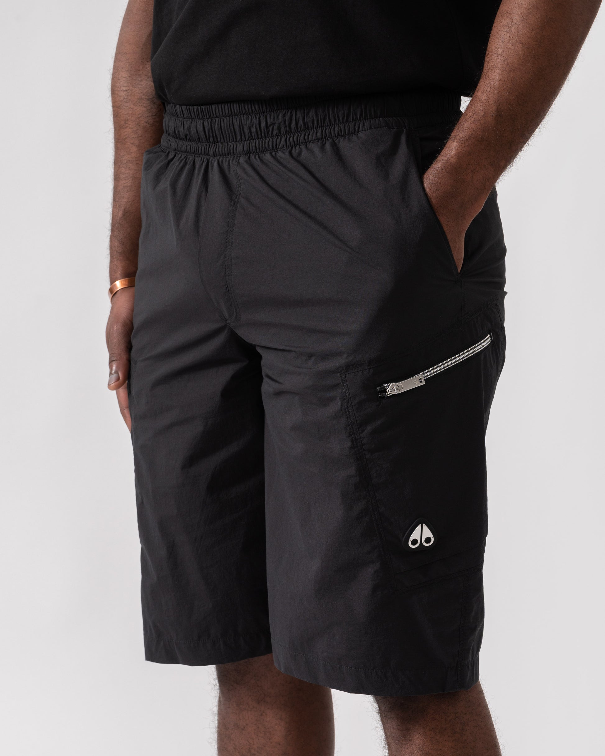 Model wearing Moose Knuckles Topflight Mens Cargo Shorts in Black 292 - pocket detail