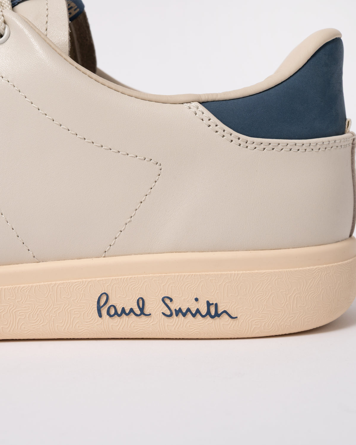Studio photograph showing heel detail of PS Paul Smith Chip Leather Mens Trainers in 01 White