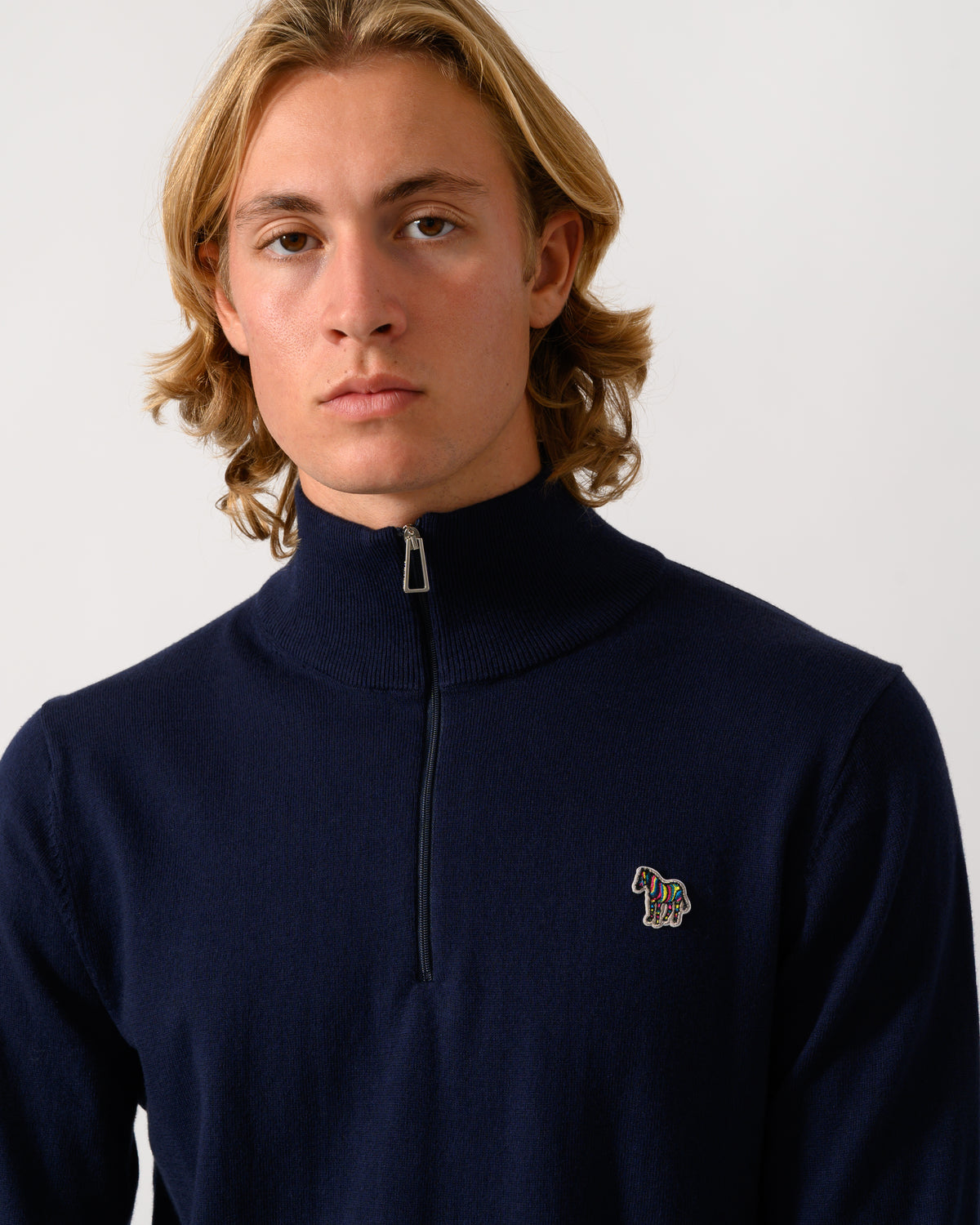 close up studio photograph of a model wearing a PS Paul Smith Mens 1/4 Zip Zebra Badge Sweater in 49 Very Dark Navy