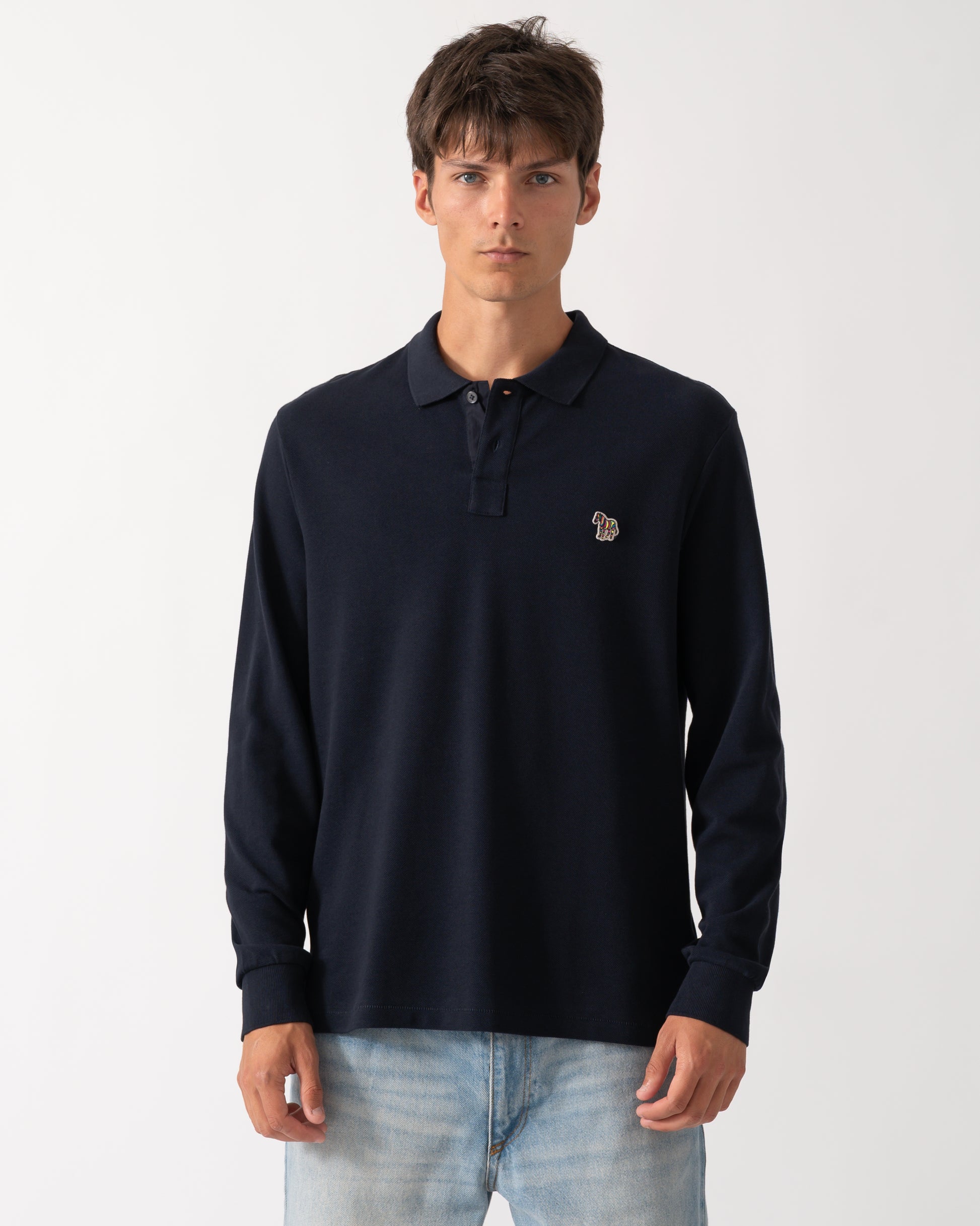 a model wearing a PS Paul Smith Mens Long Sleeve Plain Polo Shirt with Zebra Logo in 49 Very Dark Navy