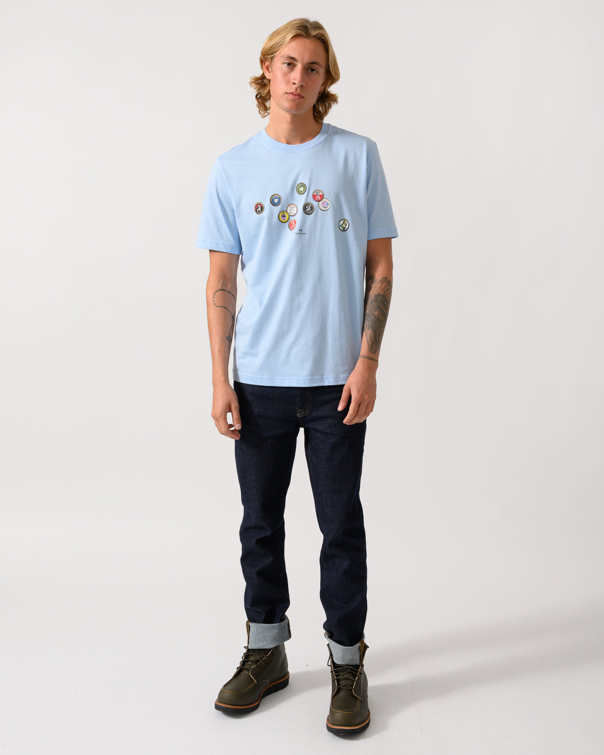 full length studio photograph of a model wearing a PS Paul Smith Mens Regular Fit Bottle Tops Graphic T-Shirt in 41E Light Blue