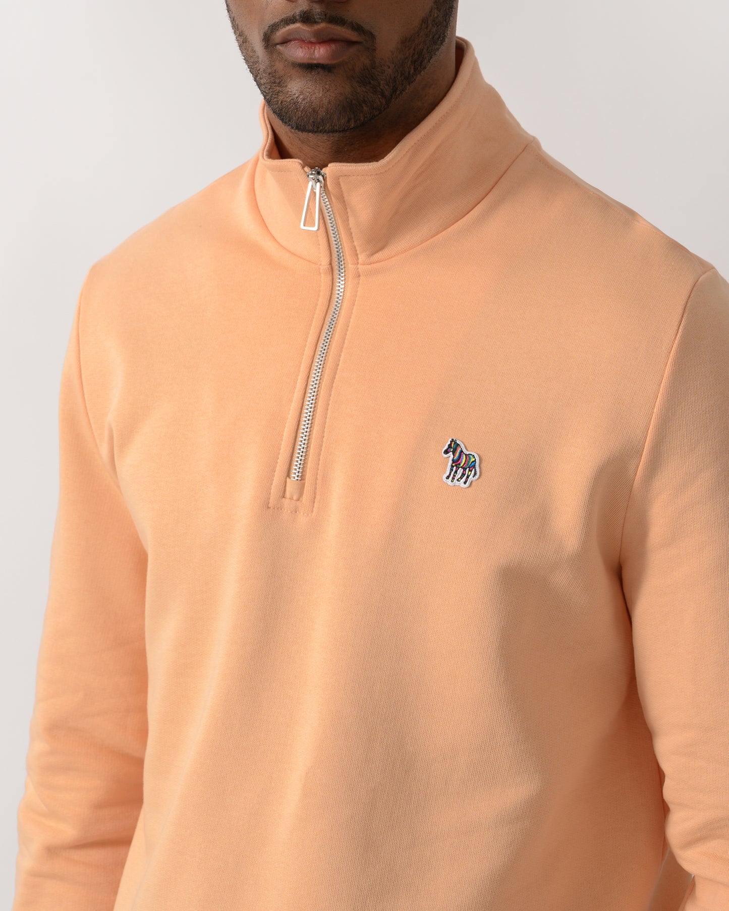 close up shot of a  model wearing a PS Paul Smith Mens Regular Fit Half Zip Zebra Logo Top in 15D Orange