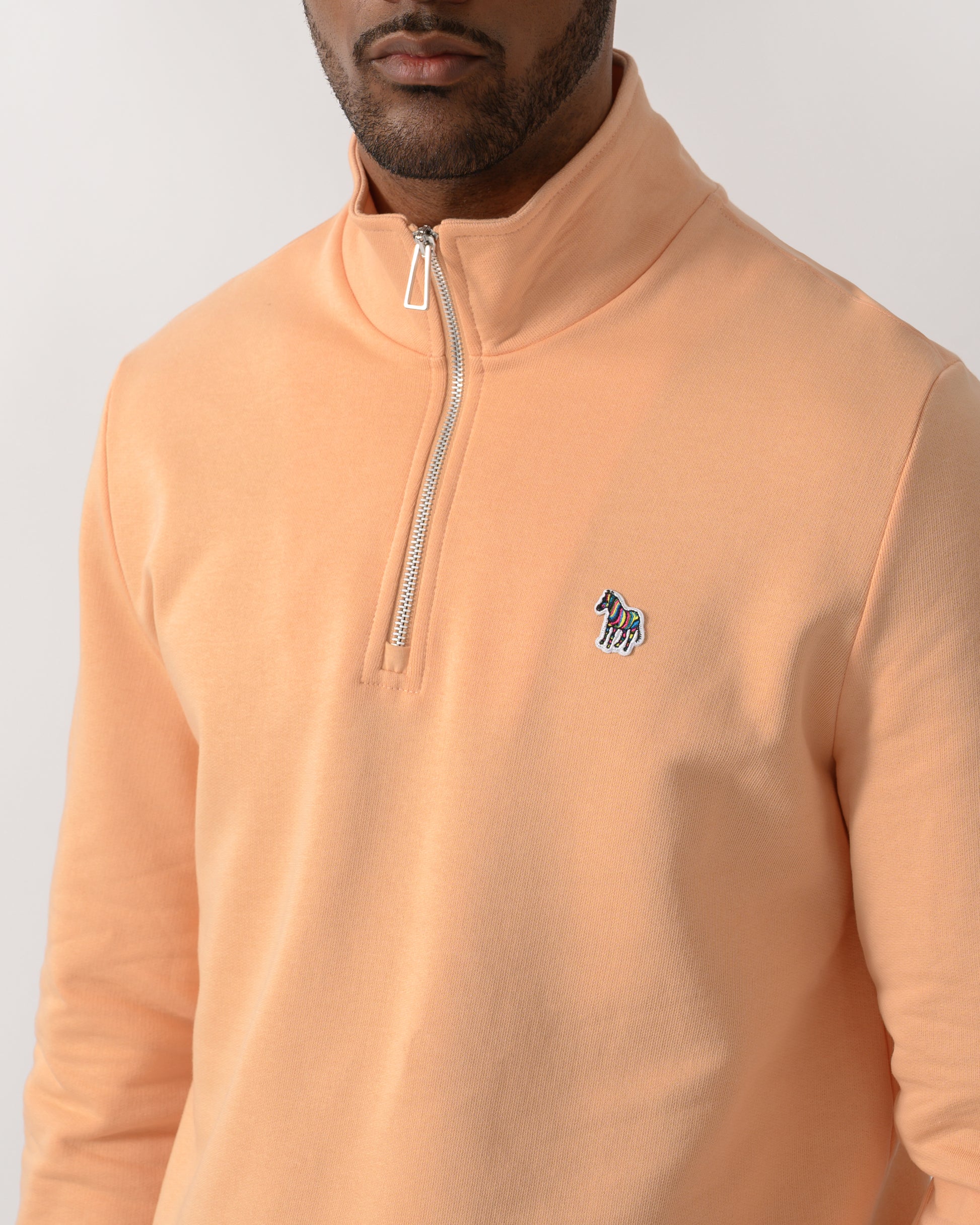 close up shot of a  model wearing a PS Paul Smith Mens Regular Fit Half Zip Zebra Logo Top in 15D Orange