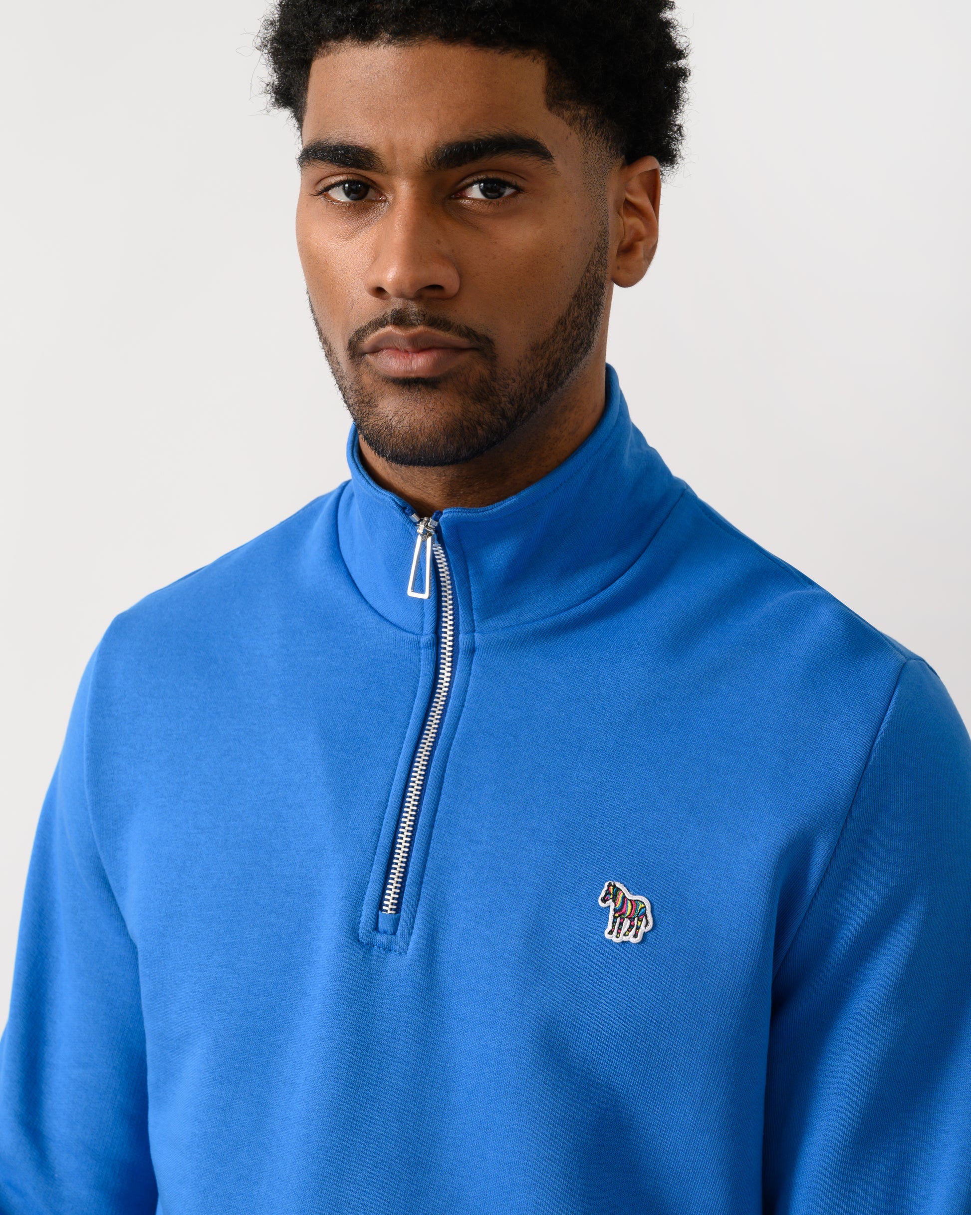 close up shot of a model wearing a PS Paul Smith Mens Regular Fit Half Zip Zebra Logo Top in 45E Blue