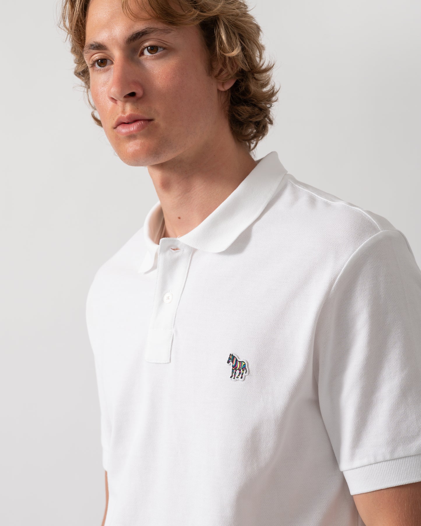 close up of model wearing a PS Paul Smith Mens Regular Fit Short Sleeve Zebra Logo Polo Shirt M2R-183K-WZEBRA in 01 White