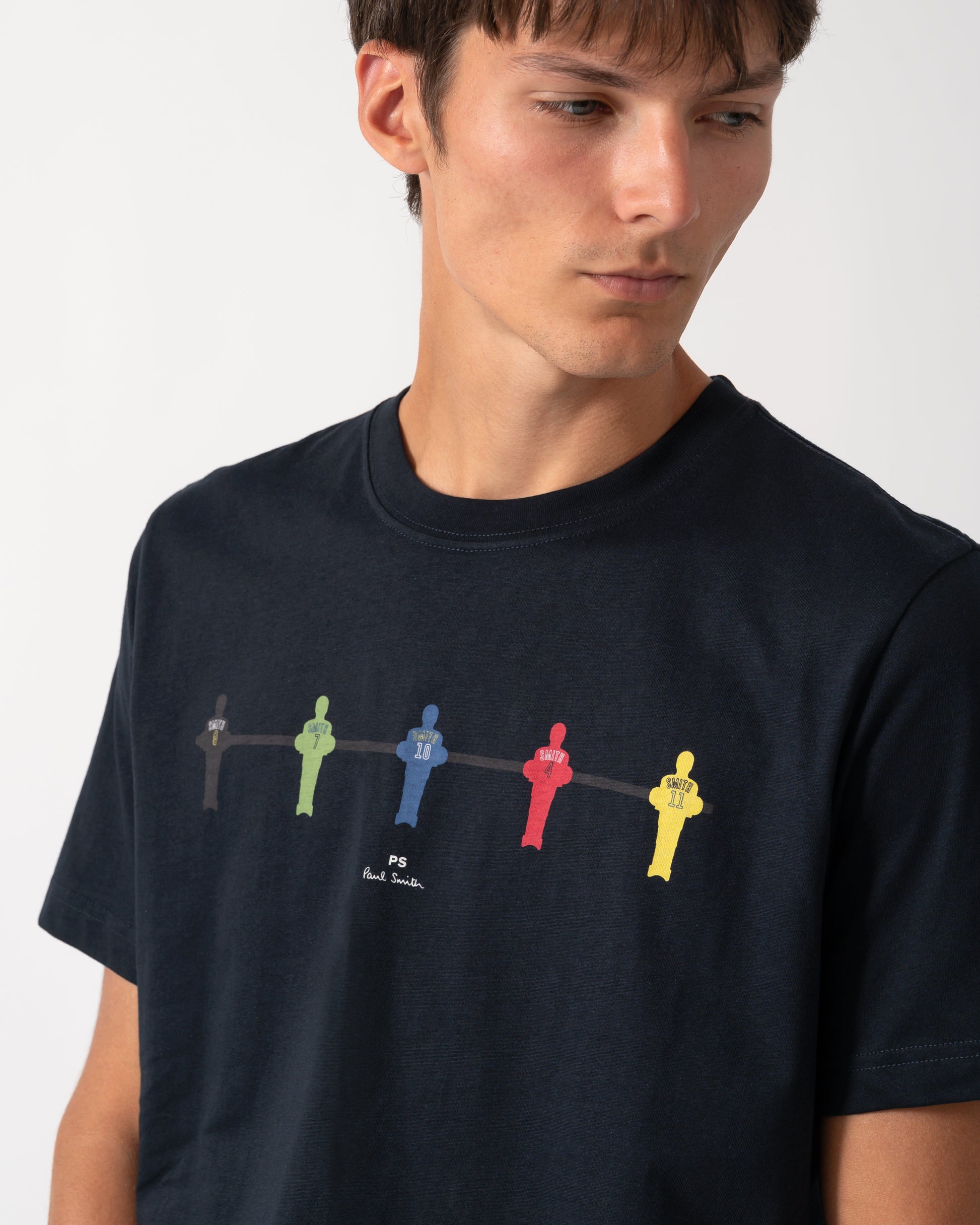 close up of a model wearing a PS Paul Smith Mens Regular Fit Table Football Graphic T-Shirt in 49 Very Dark Navy