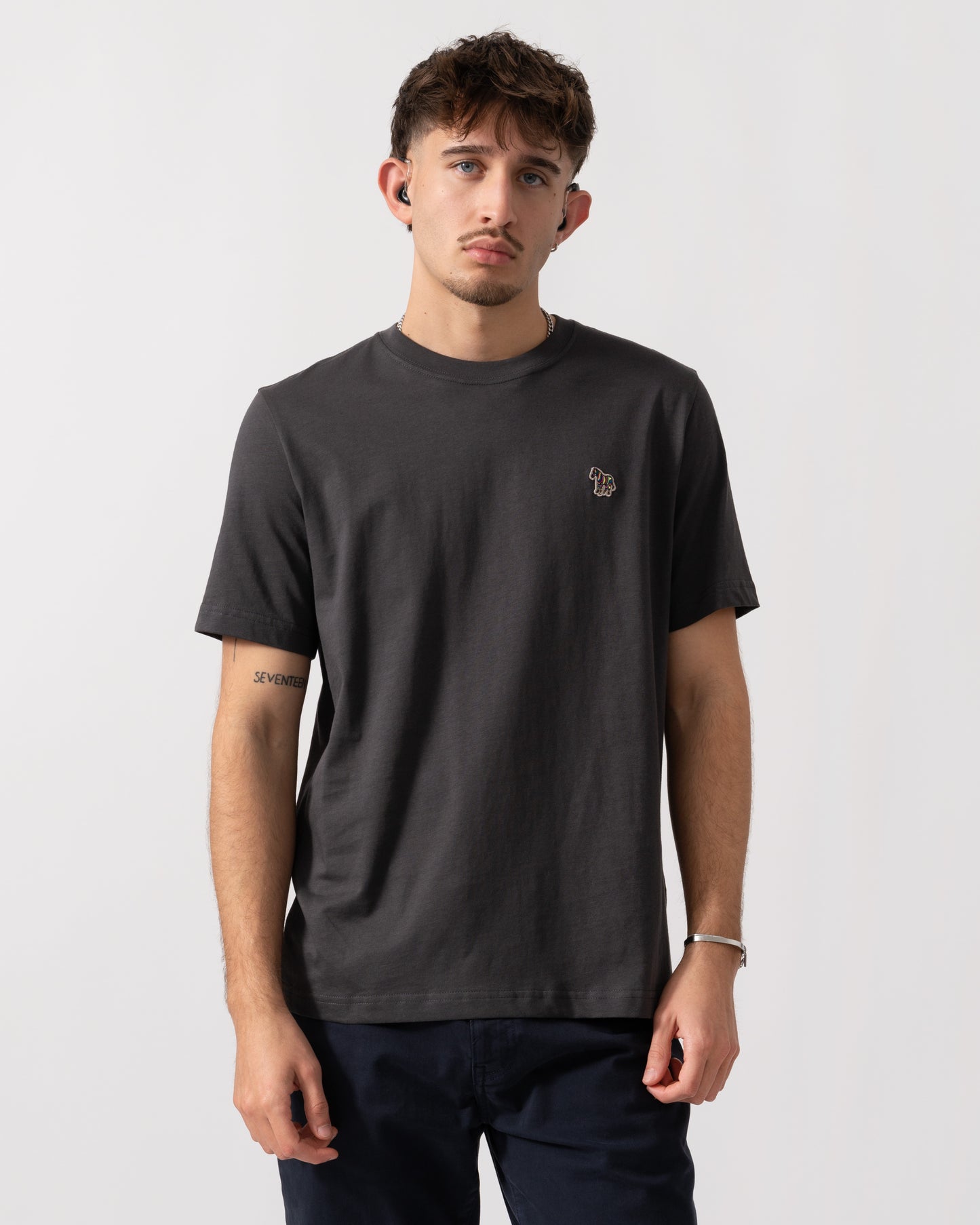 Man wearing a dark gray t-shirt with a small logo on a white background