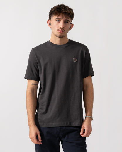 Man wearing a dark gray t-shirt with a small logo on a white background