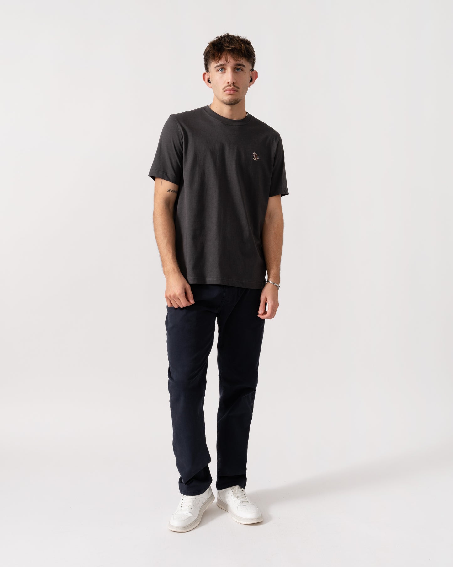 Man wearing a black t-shirt and dark pants on a white background