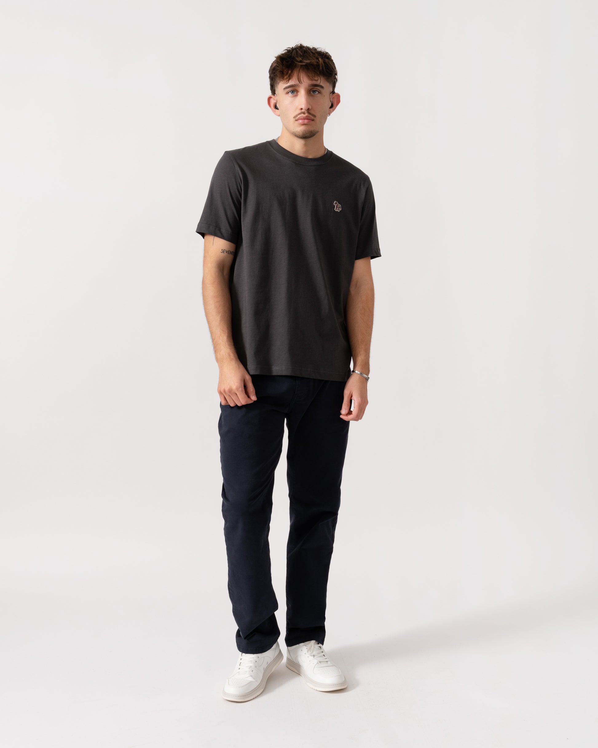 Man wearing a black t-shirt and dark pants on a white background