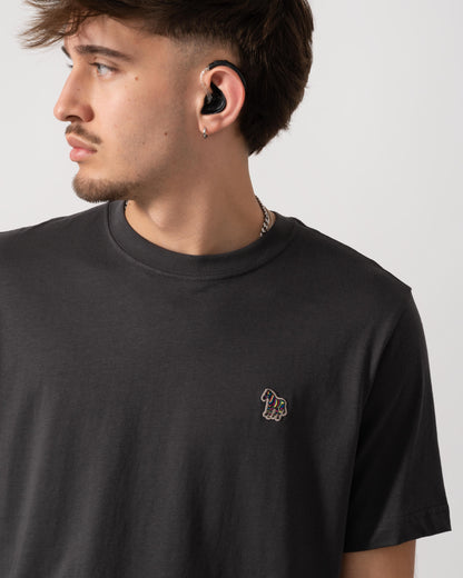 Man wearing a black t-shirt with a small logo on a plain background