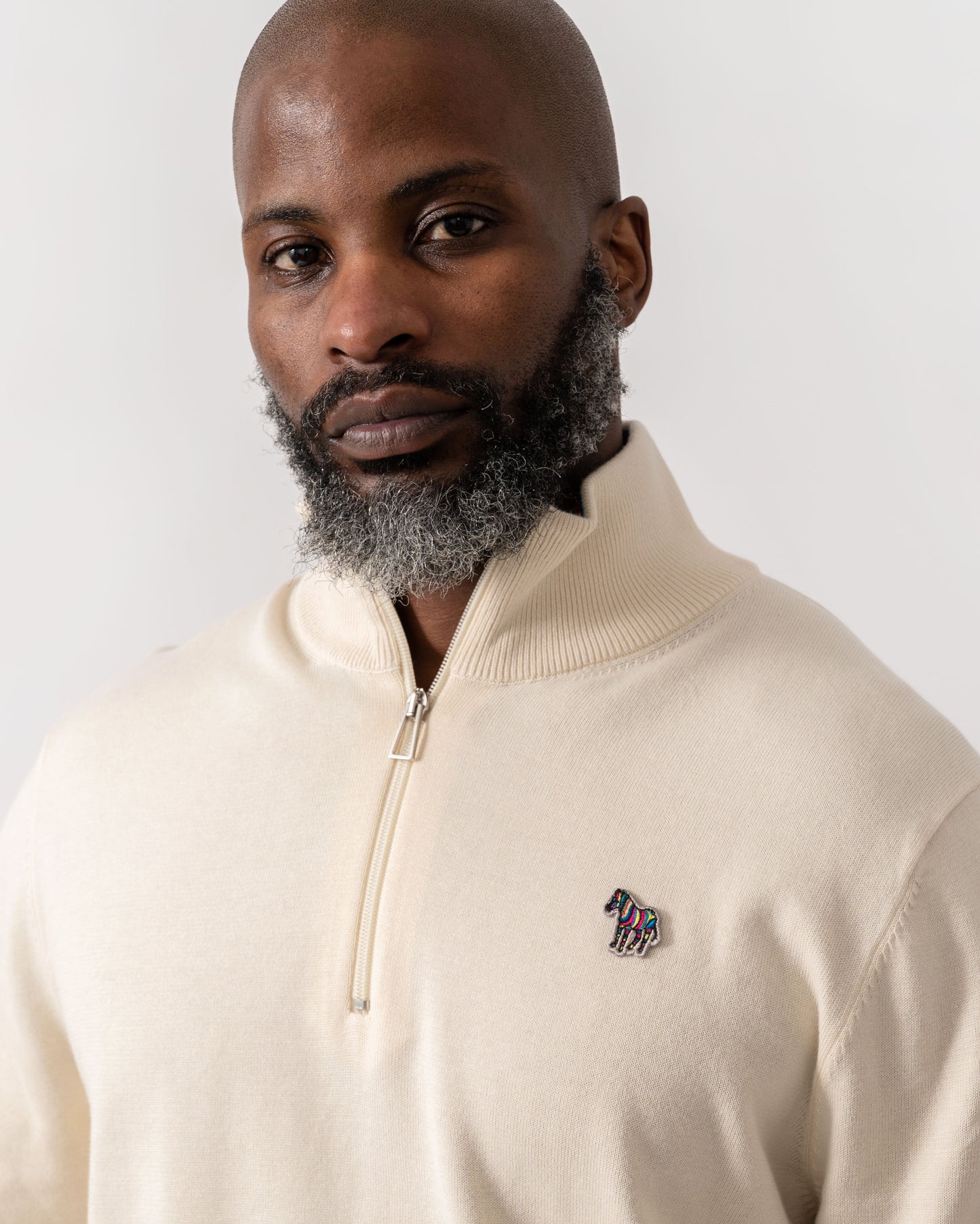 Model wearing PS Paul Smith Mens Zip Neck Zebra Badge Sweater in 04 White -detail
