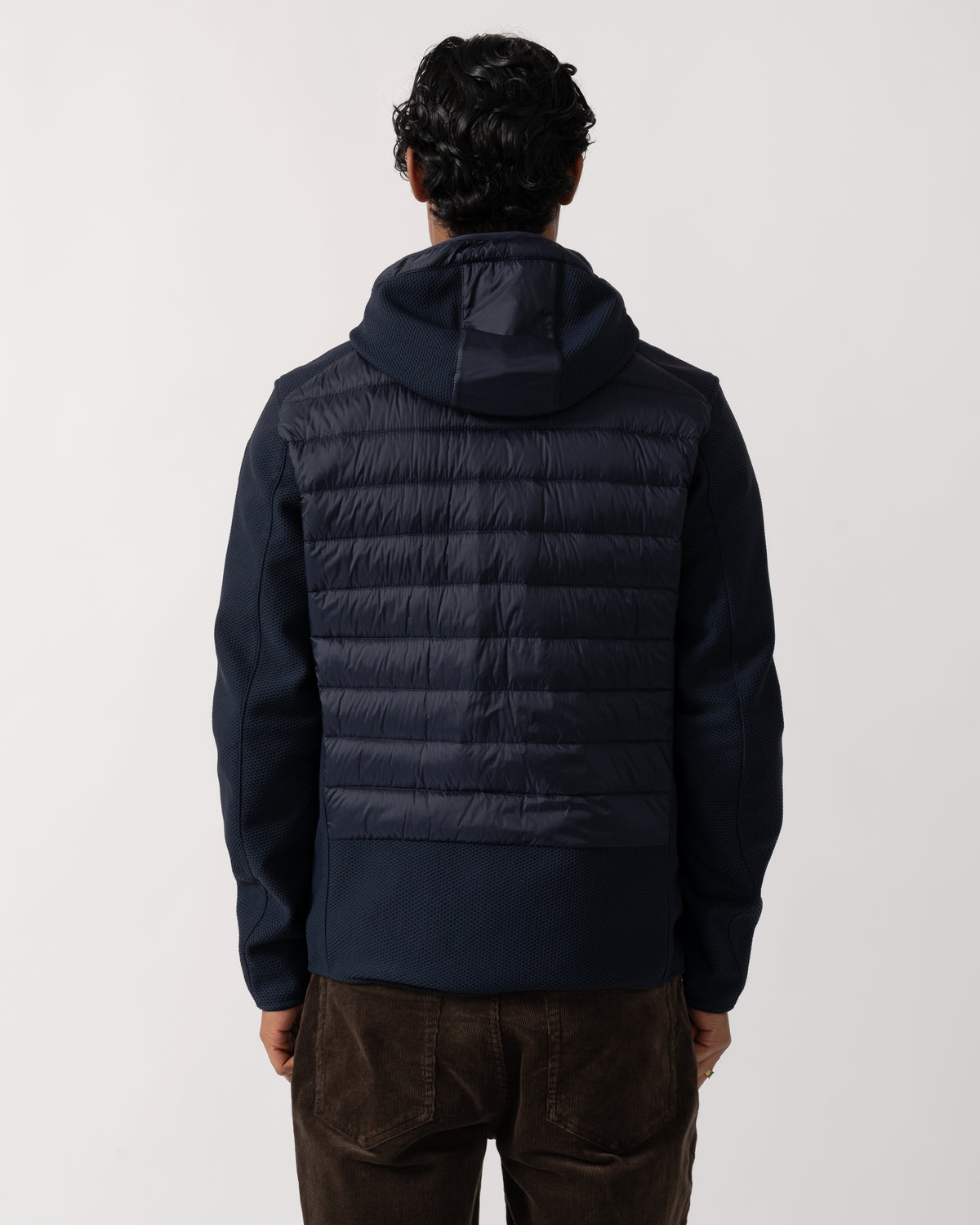 Studio photograph showing the back of a model wearing a Parajumpers Nolan Mens Hybrid Hooded Jacket in Blue Navy 316