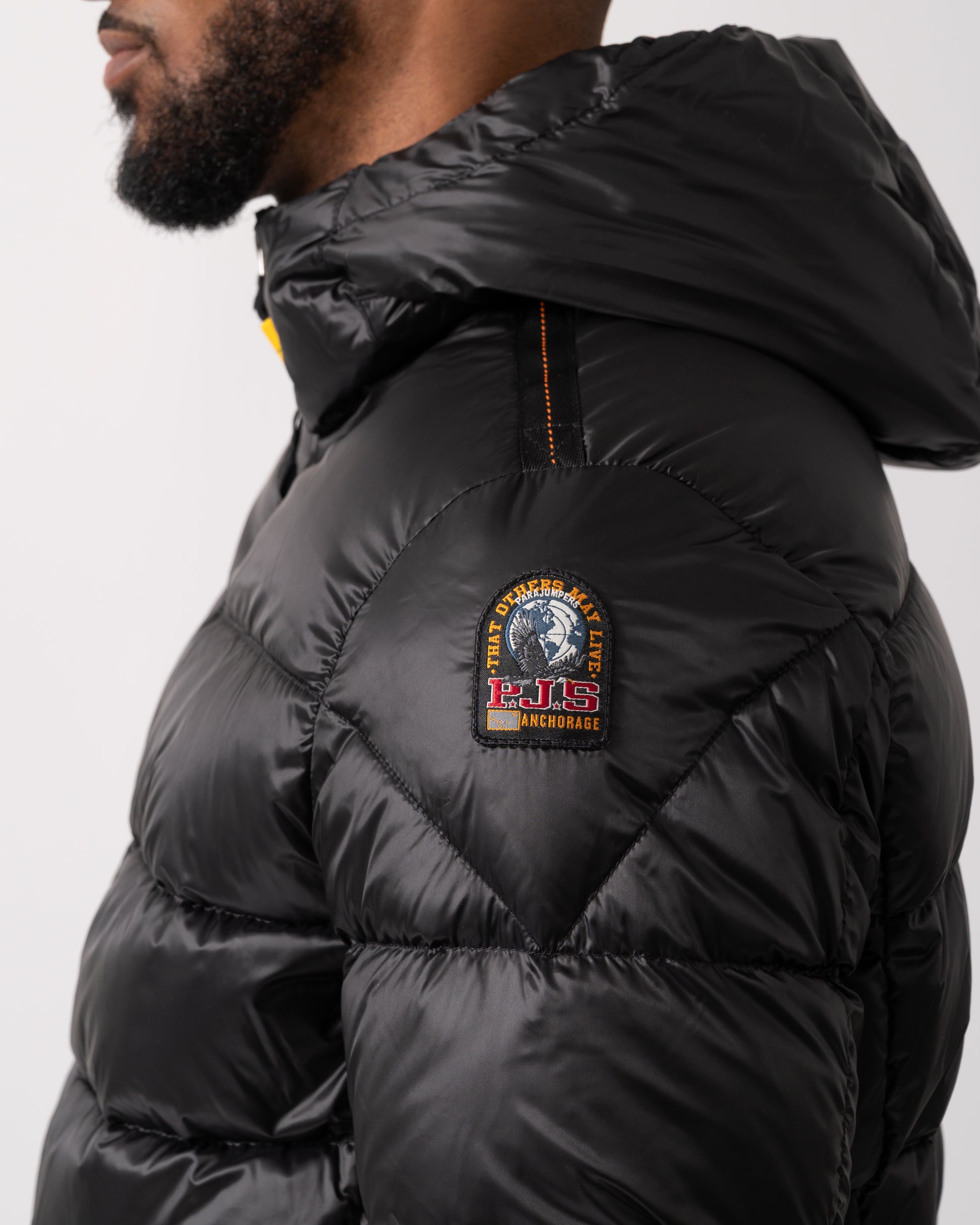 logo detail shot of a Parajumpers Pharrell Mens Hooded Down Bomber in Black