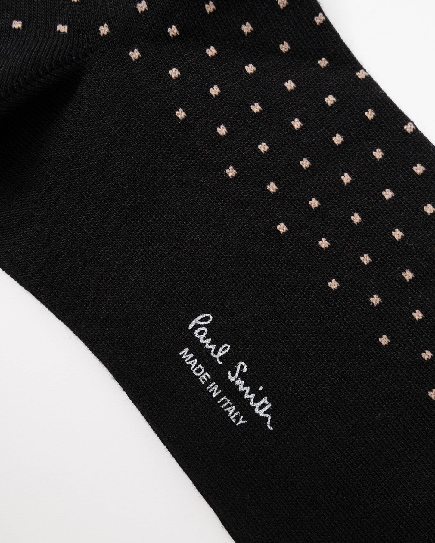 Close-up of a black knit sock with small beige geometric dot patterns and white 'Paul Smith' branding on a white background.