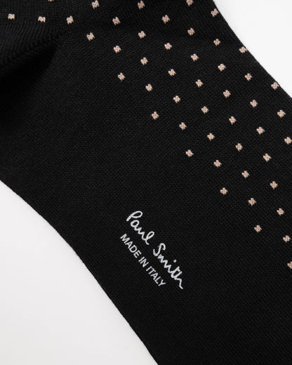 Close-up of a black knit sock with small beige geometric dot patterns and white 'Paul Smith' branding on a white background.