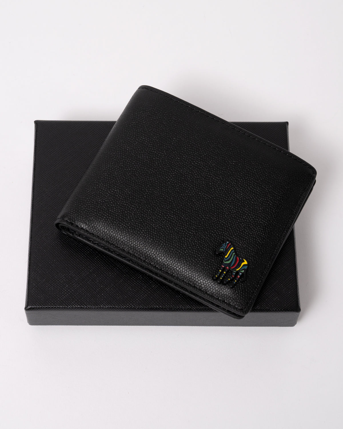 studio photograph showing a Paul Smith Mens Zebra Badge Billfold Wallet in 79 Black with its packaging