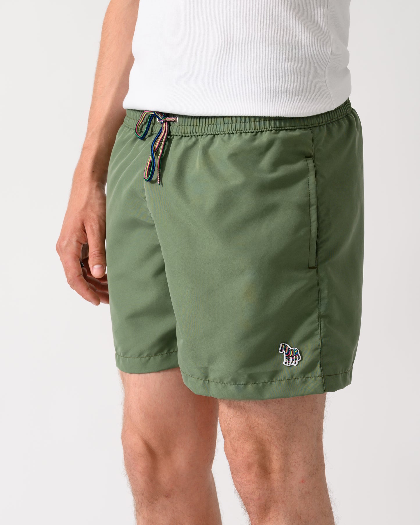 close up shot of a model wearing a pair of Paul Smith Mens Zebra Logo Swim Shorts in 35A Green