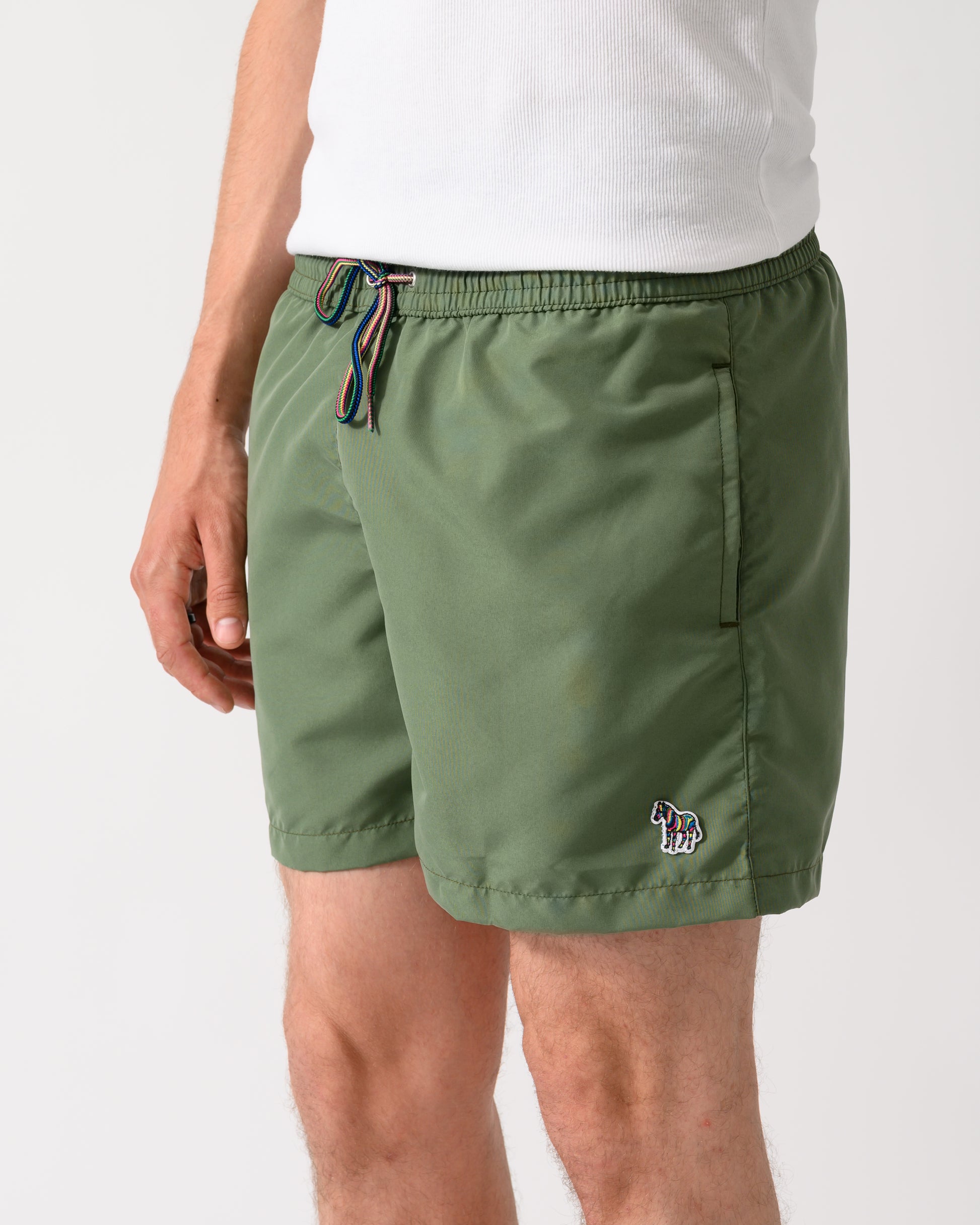 close up shot of a model wearing a pair of Paul Smith Mens Zebra Logo Swim Shorts in 35A Green