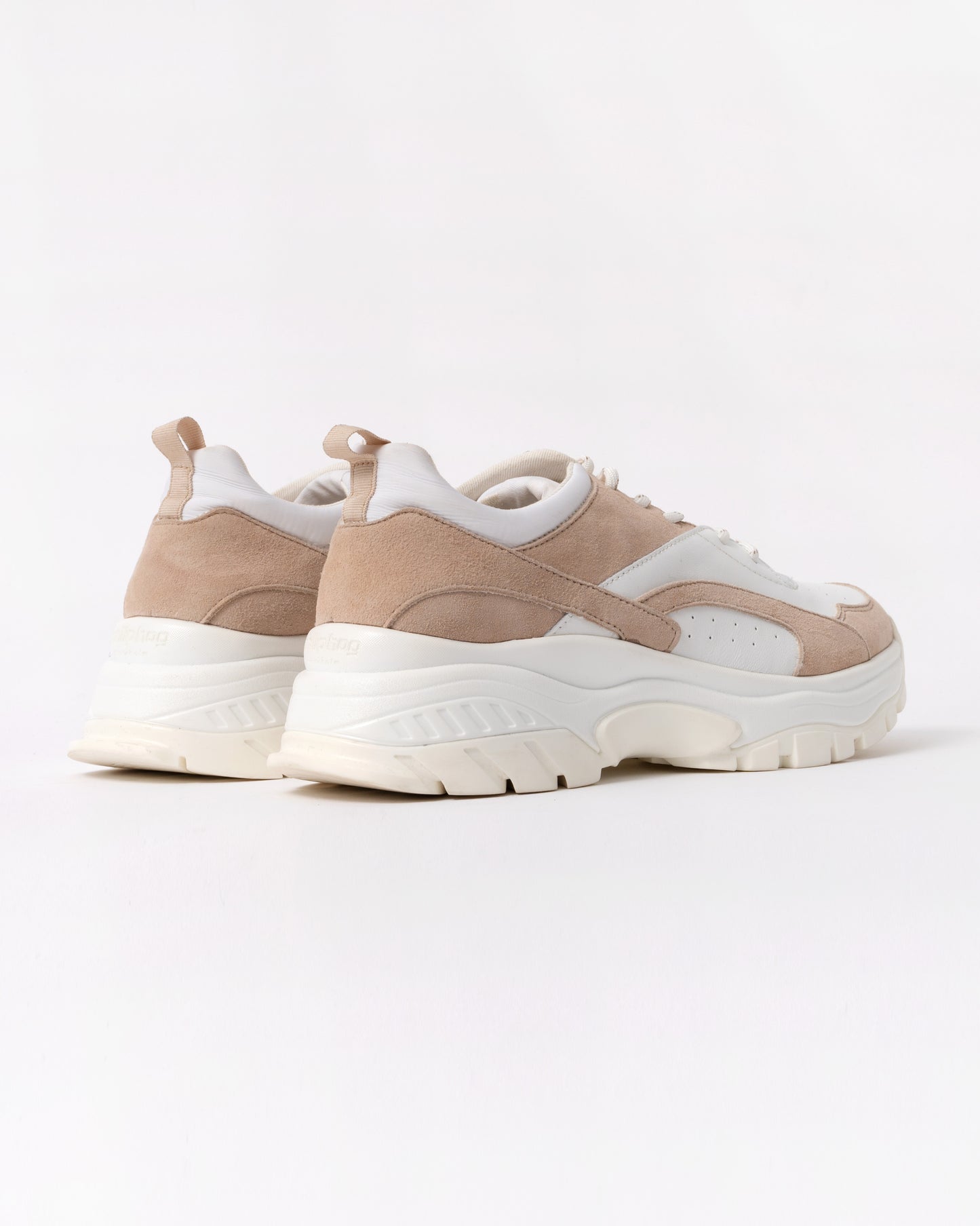 Pair of beige and white sneakers on a light gray background
