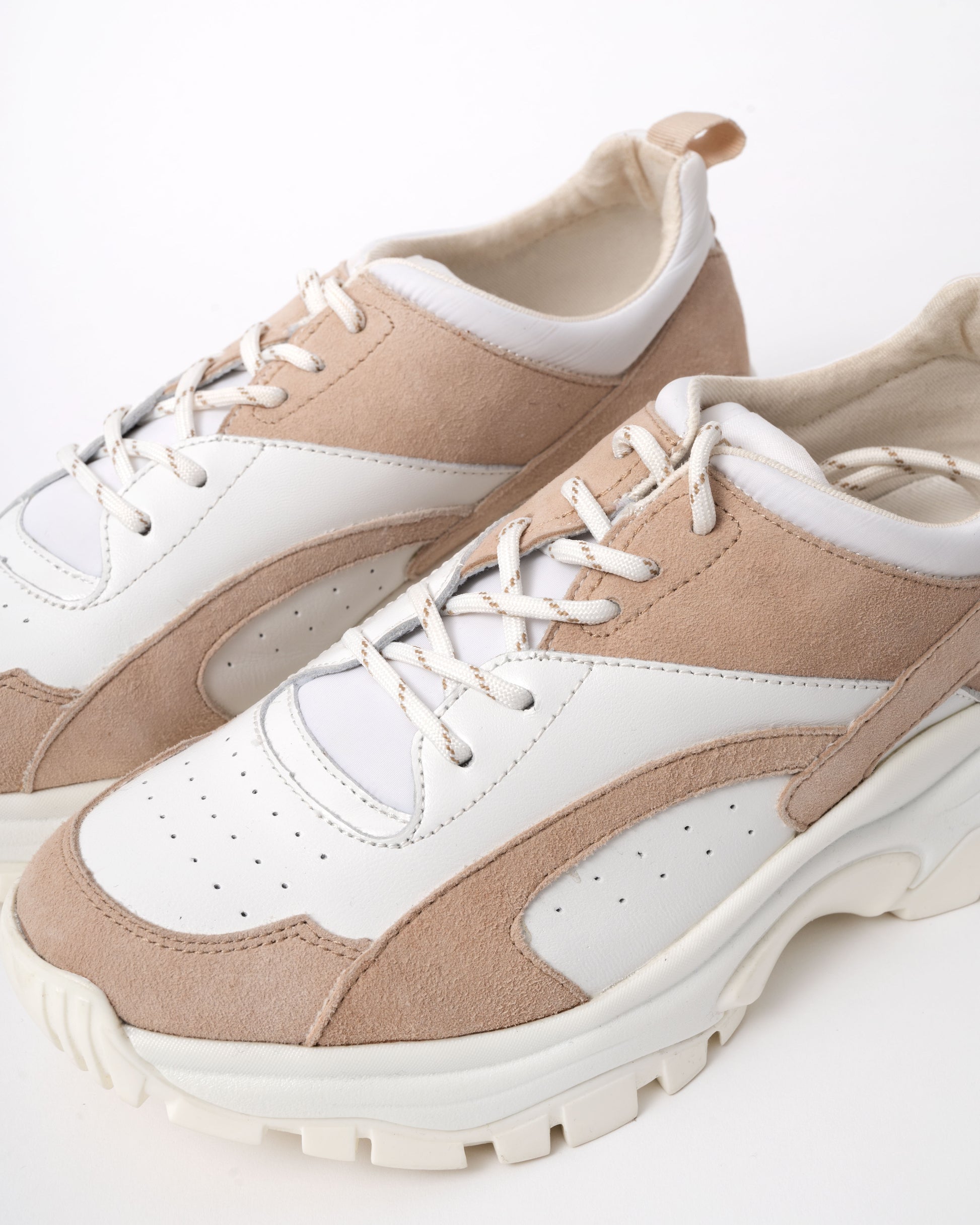 Pair of beige and white sneakers on a light background