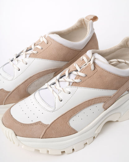 Pair of beige and white sneakers on a light background
