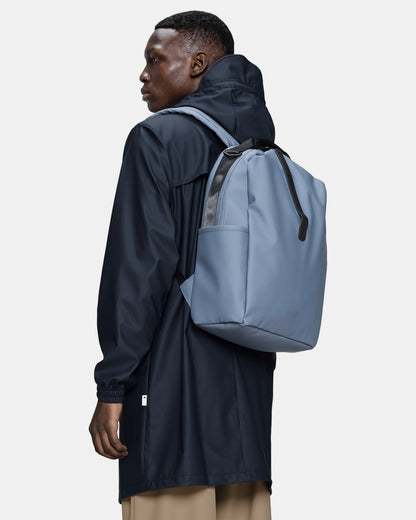 model carrying a Rains Clip Front Backpack in 172 Blue Dusk