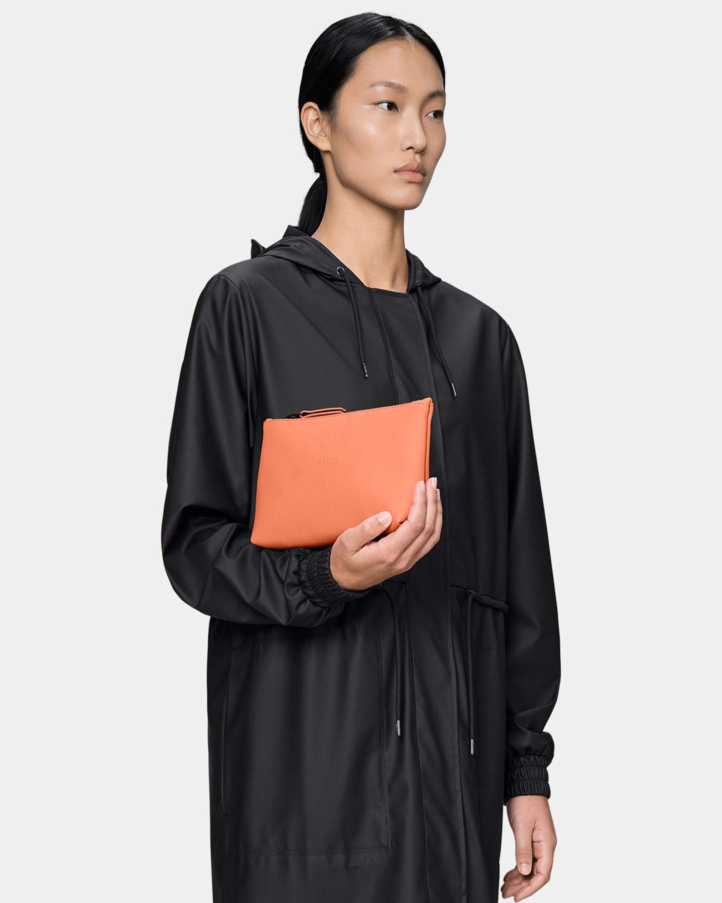 model holding a Rains Cosmetic Bag in 174 Ember