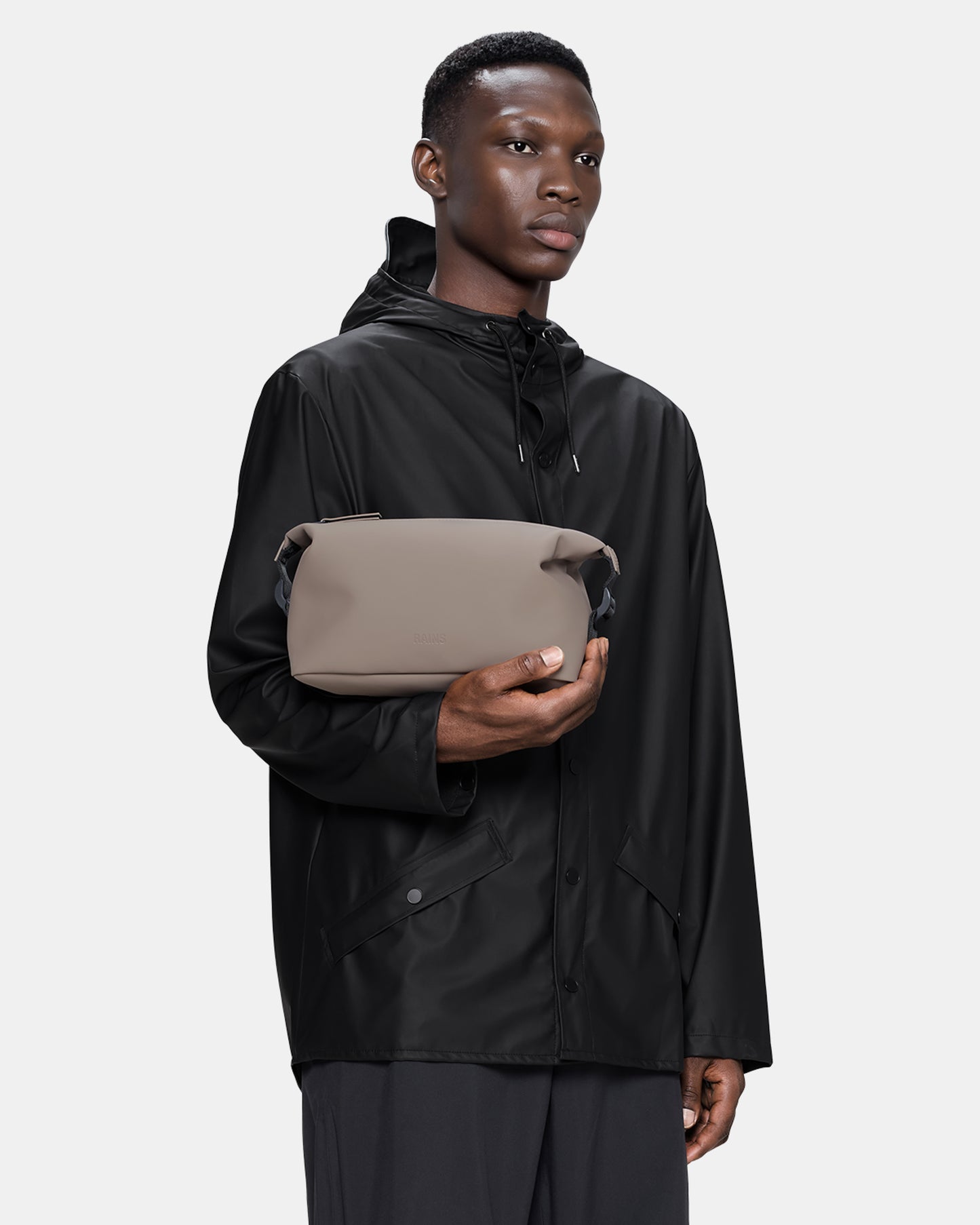 model holding a Rains Hilo Wash Bag in 173 Cinder