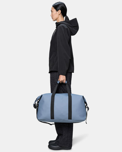 model holding a Rains Hilo Weekend Bag in 172 Blue Dusk