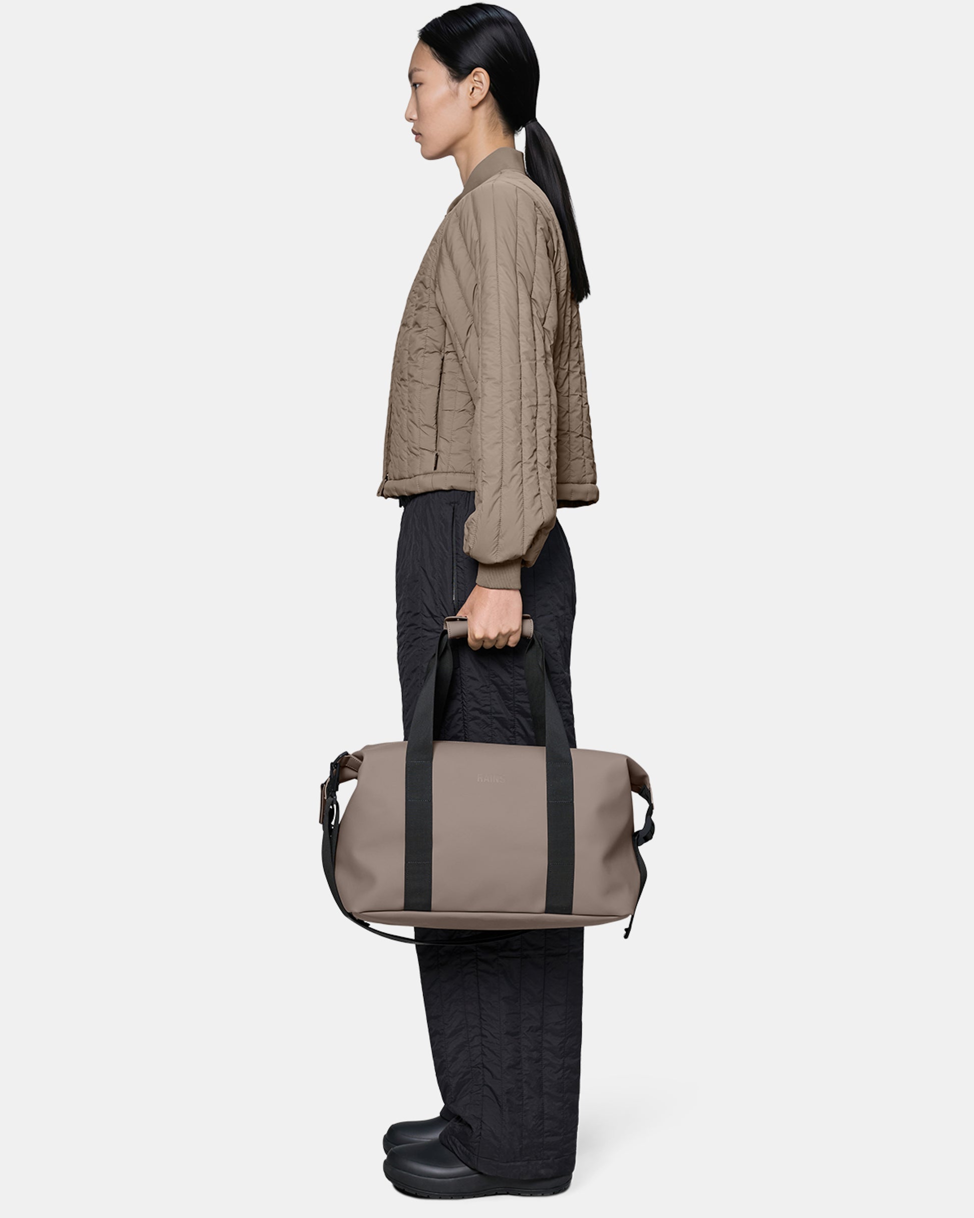 model holding a Rains Hilo Weekend Bag Small in 173 Cinder