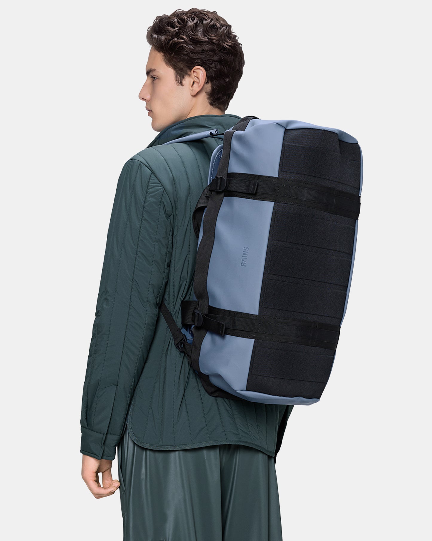 model wearing a Rains Texel Duffel Bag Small in 172 Blue Dusk