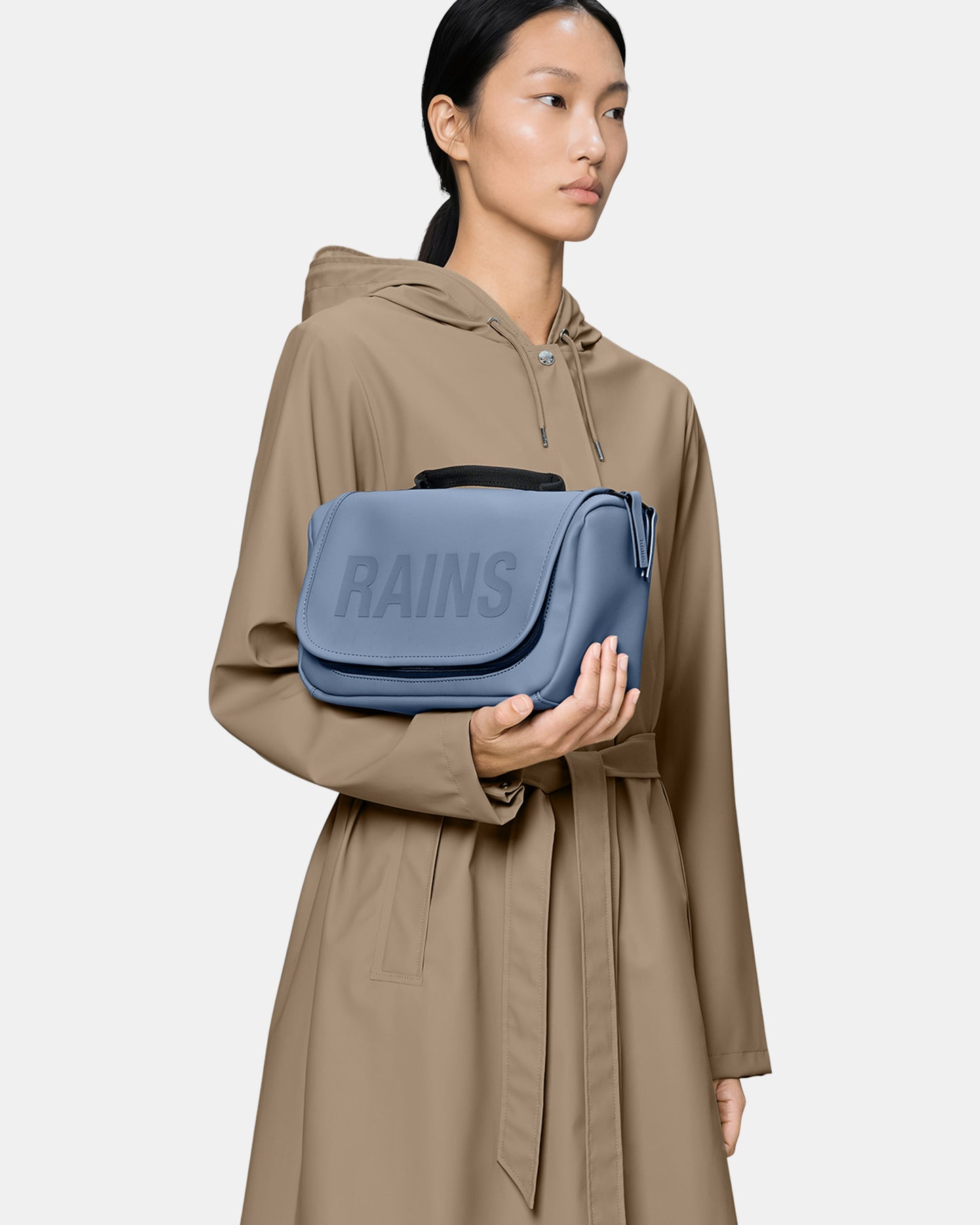 model holding a Rains Texel Wash Bag in 172 Blue Dusk