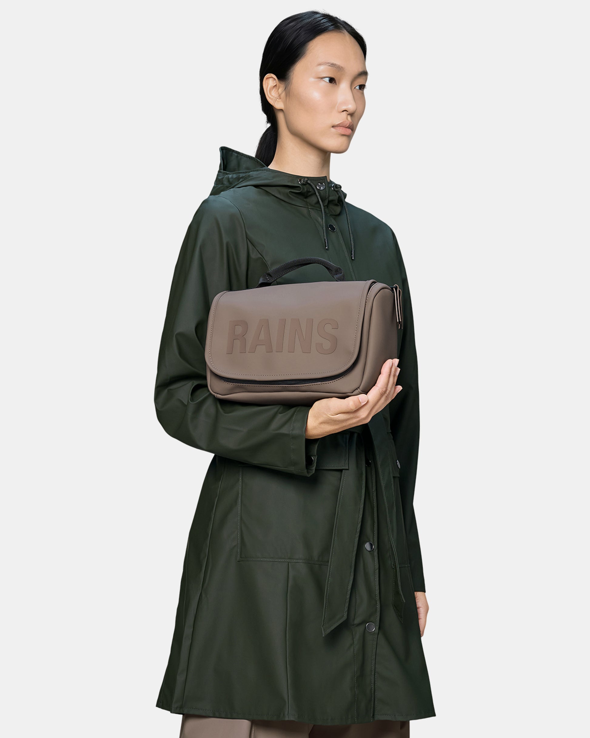 model holding a Rains Texel Wash Bag in 173 Cinder