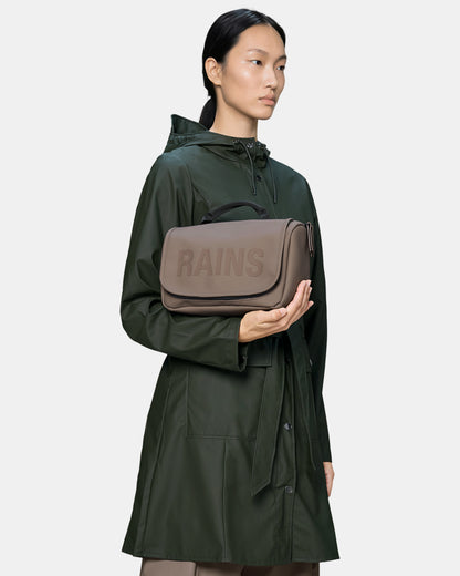 model holding a Rains Texel Wash Bag in 173 Cinder