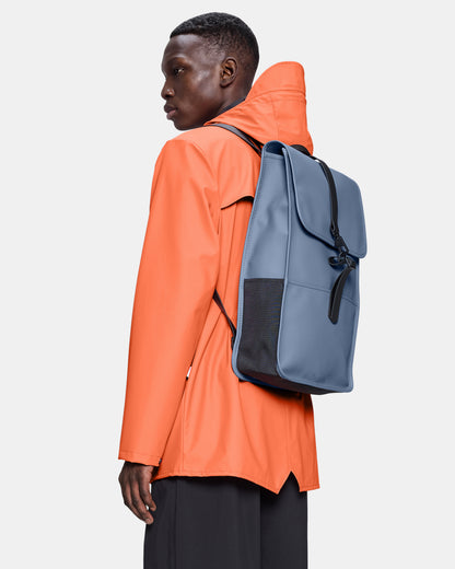model wearing a Rains Unisex Backpack in 172 Blue Dusk