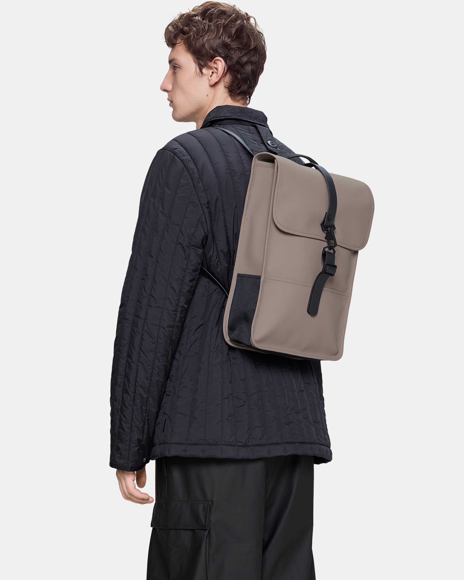 model carrying a Rains Unisex Backpack Mini in 173 Cinder