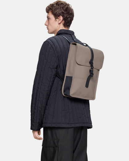 model carrying a Rains Unisex Backpack Mini in 173 Cinder