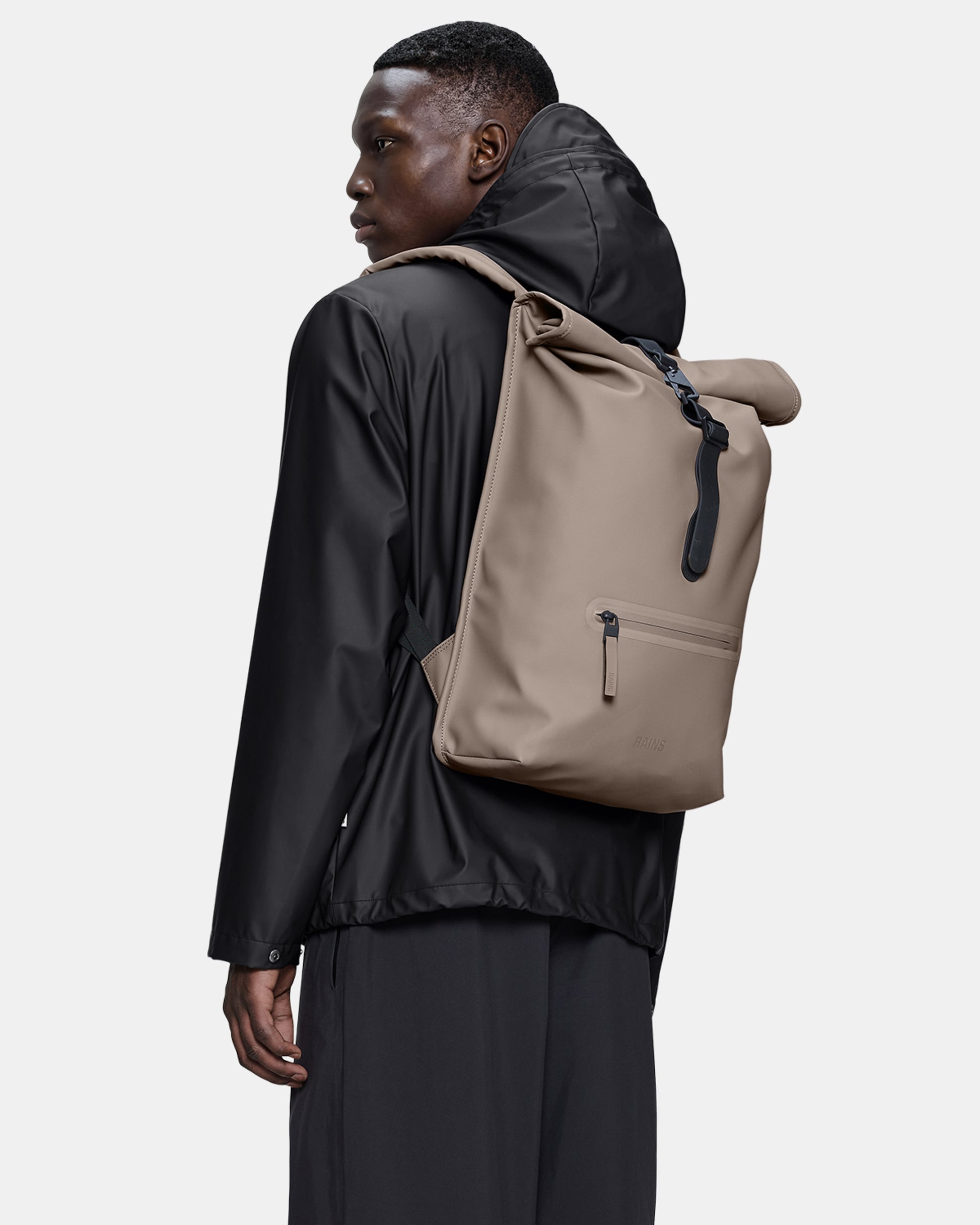 model carrying a Rains Unisex Rolltop Rucksack in 173 Cinder